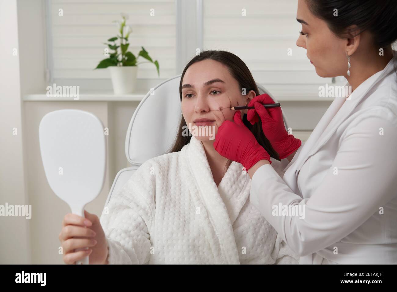 Cosmetologist using facial marker on patient face before beauty