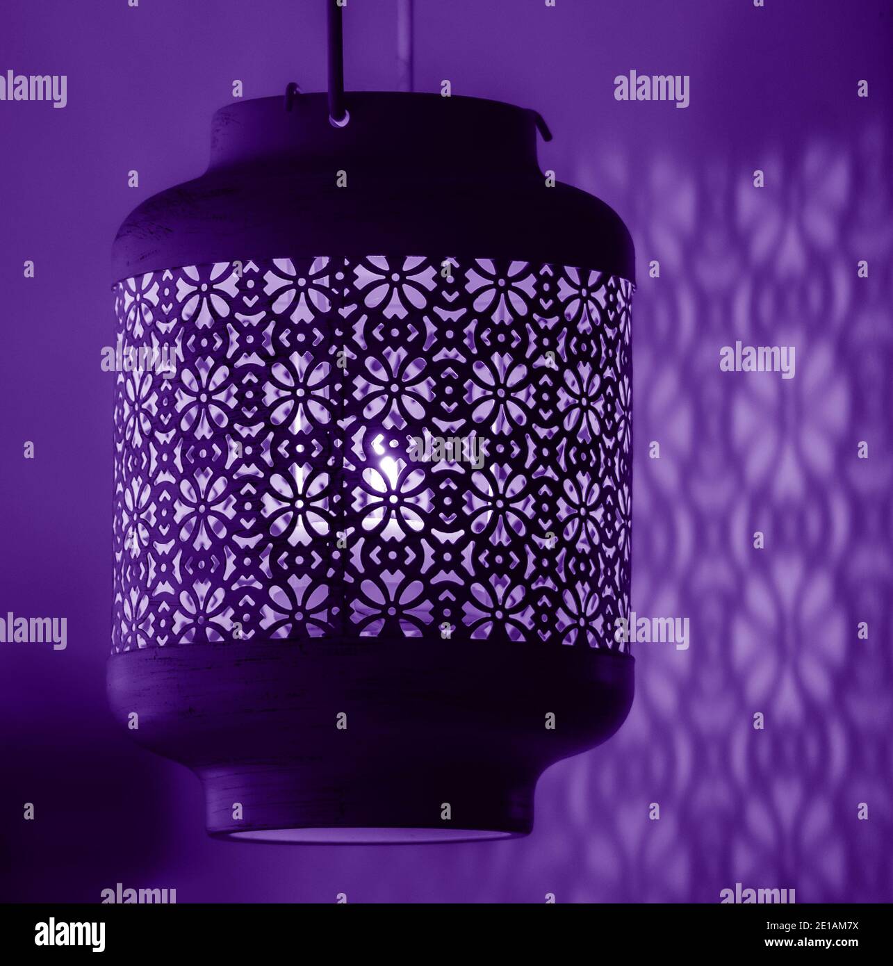 Candle light lamp with beautiful detailed antique patterns designs casting shadows over the near wall Stock Photo