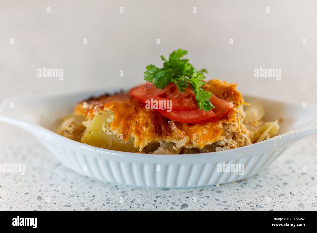 Closeup shot featuring delicately set side dish, garnished with tomatoes, and green leaves on top, with the plate set on marble shelf Stock Photo