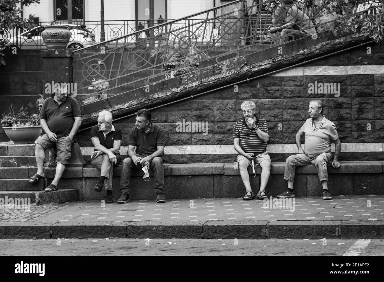 Zafferana etnea, Italy - 07 2020: Men chatting outdoor holding masks Stock Photo