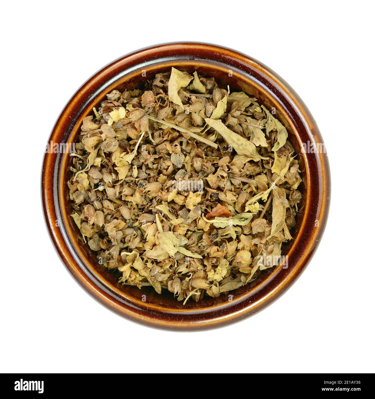 Dried natural basil spice in a ceramic bowl (Ocimum basilicum). Pile of dried basil seasoning