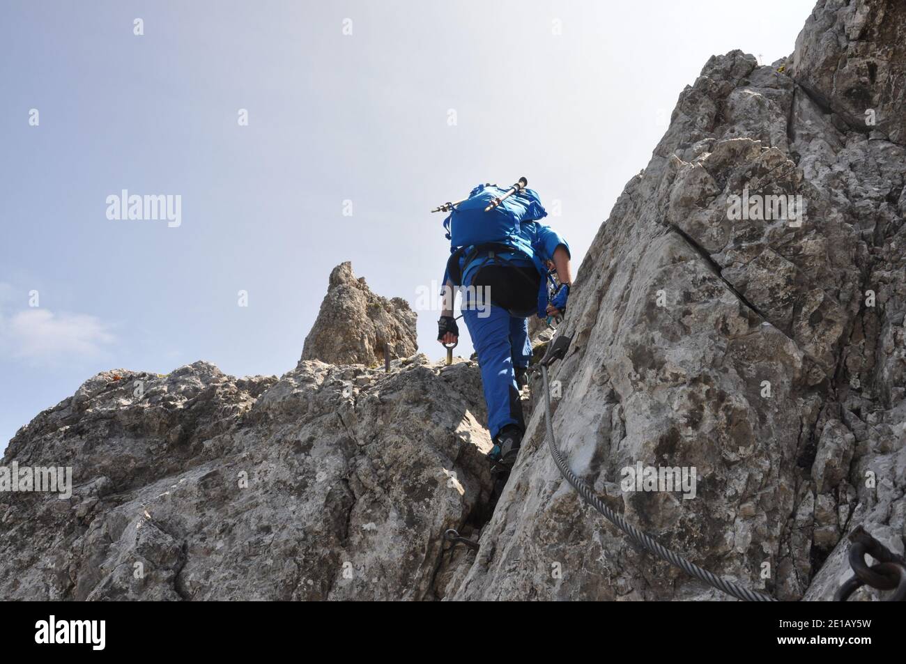 A girl in a blue suit on via ferrata in Dolomiti, Italy Stock Photo