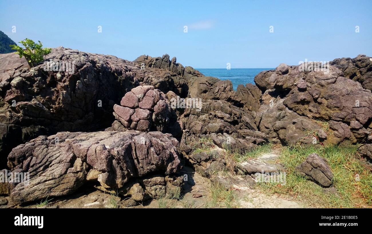 Many rocks in the seashore before the ocean in a sunny bright day Stock Photo