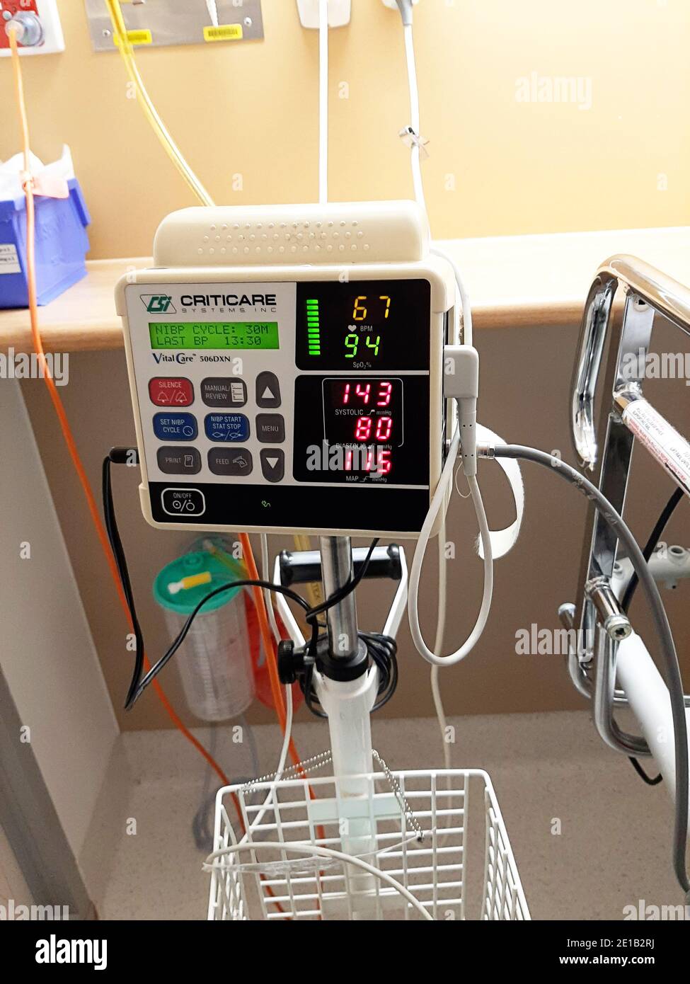 Blood pressure monitor at a hospital bedside, in use with measurements visible Stock Photo