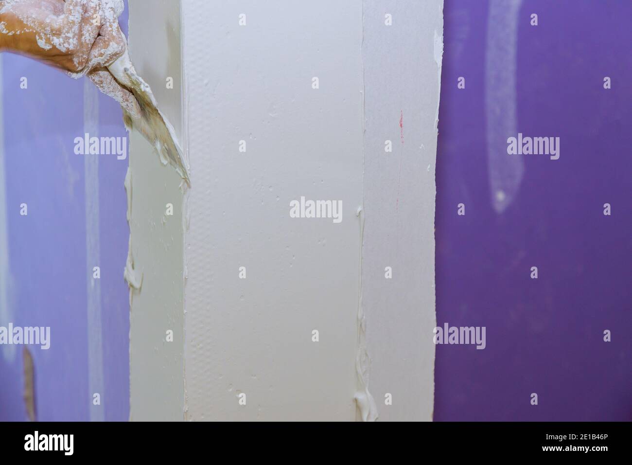 Construction worker plaster with trowel to gypsum board puts a finishing touch in the wall Stock