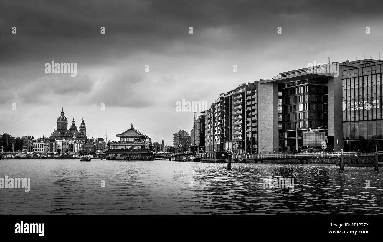 Black and White Photo of Modern Office Buildings and a floating Chinese Restaurant along the Harbor named Het IJ in Amsterdam, the Netherlands Stock Photo