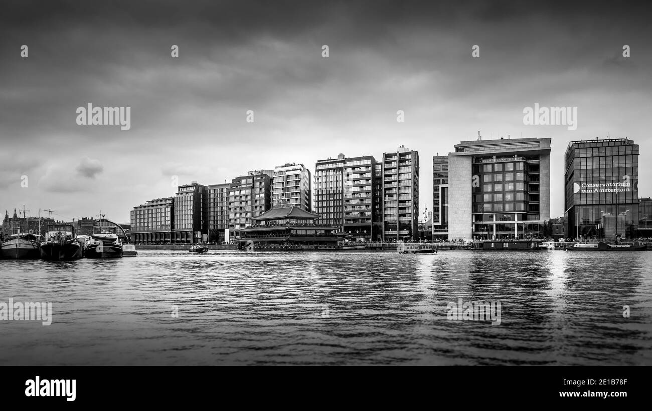 Black and White Photo of Modern Office Buildings and a floating Chinese Restaurant along the Harbor named Het IJ in Amsterdam, the Netherlands Stock Photo