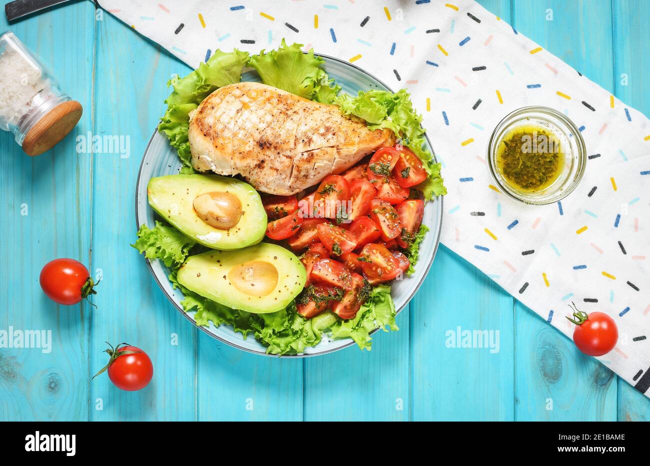 Caprese lunch bowl with grilled chicken and avocado on blue wooden background. Top view Stock Photo
