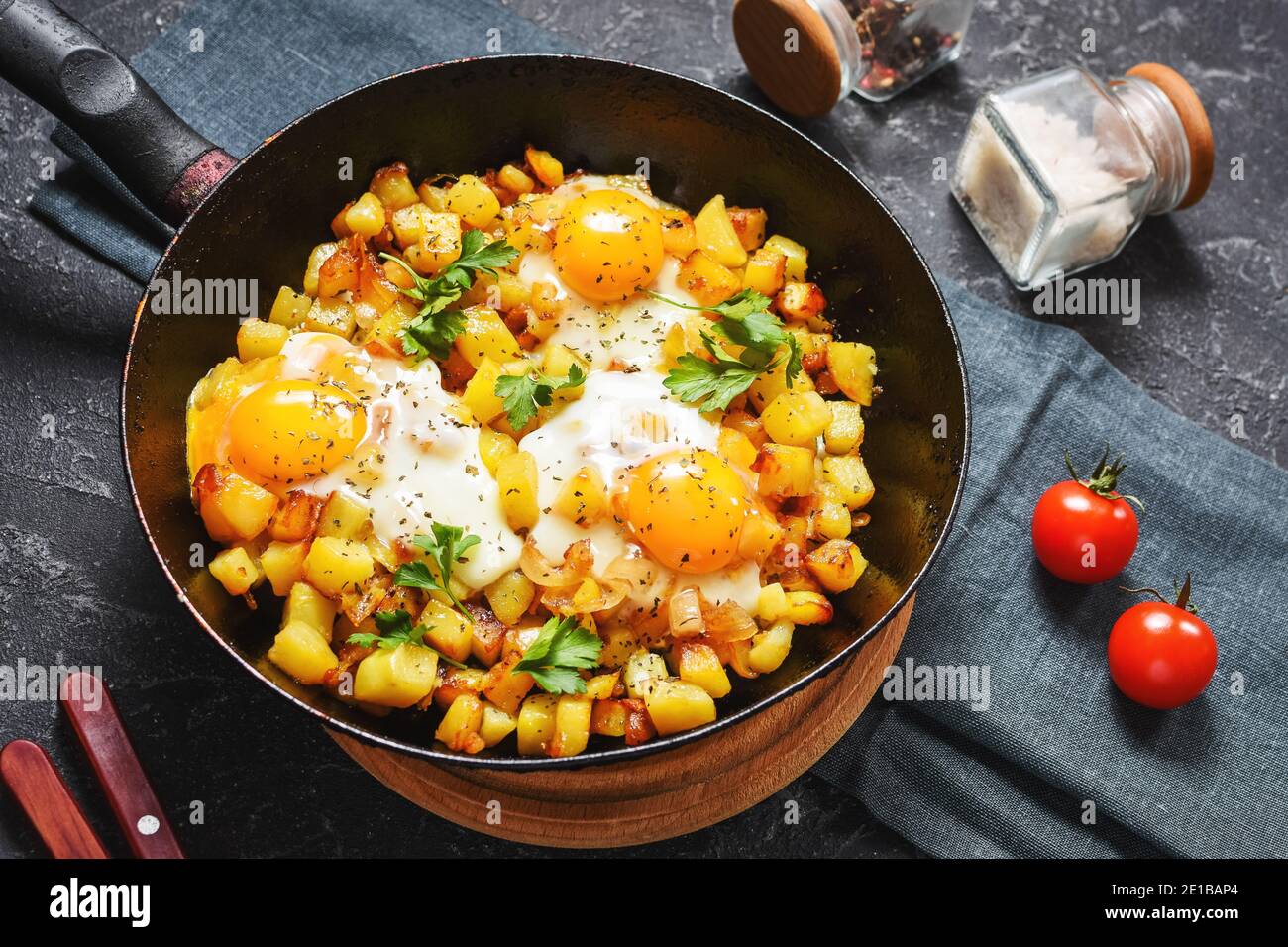 Potato hash with eggs and herbs for breakfast on a black stone background Stock Photo