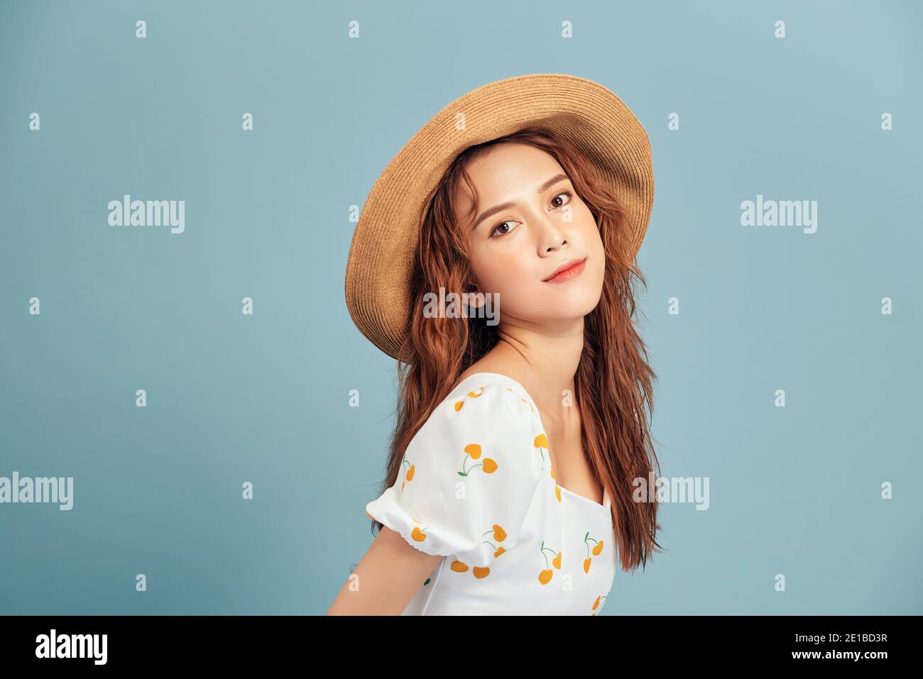 Portrait of young Asian woman wearing straw hat and summer dress over ...