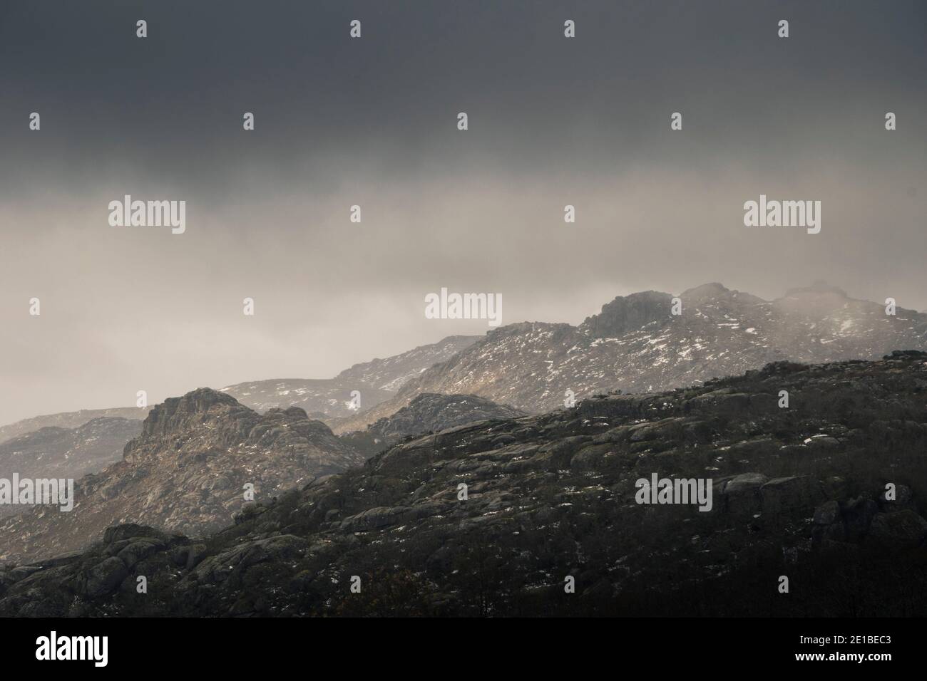 Mountain landscape with snowy capes on a foggy rainy day, as the light enters though the clouds Stock Photo