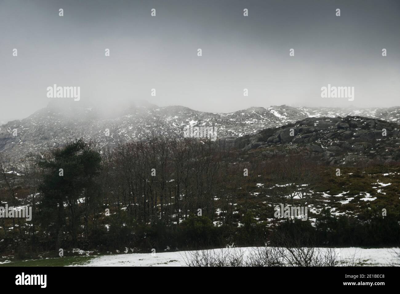 Mountain landscape with snowy capes on a foggy rainy day, as the light enters though the clouds Stock Photo