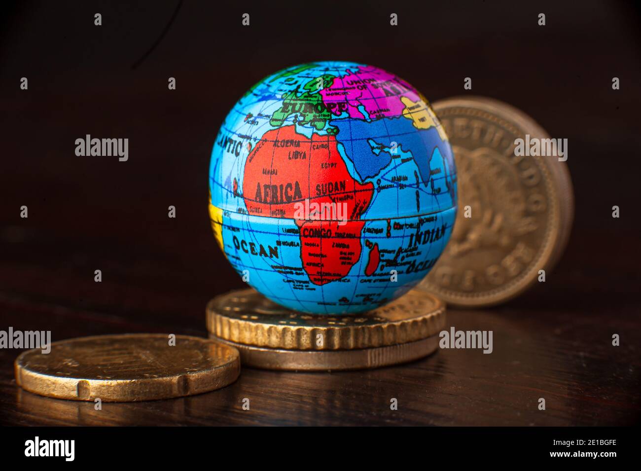 Money rules the world globe miniature mini earth with coins. Concept. Stock Photo