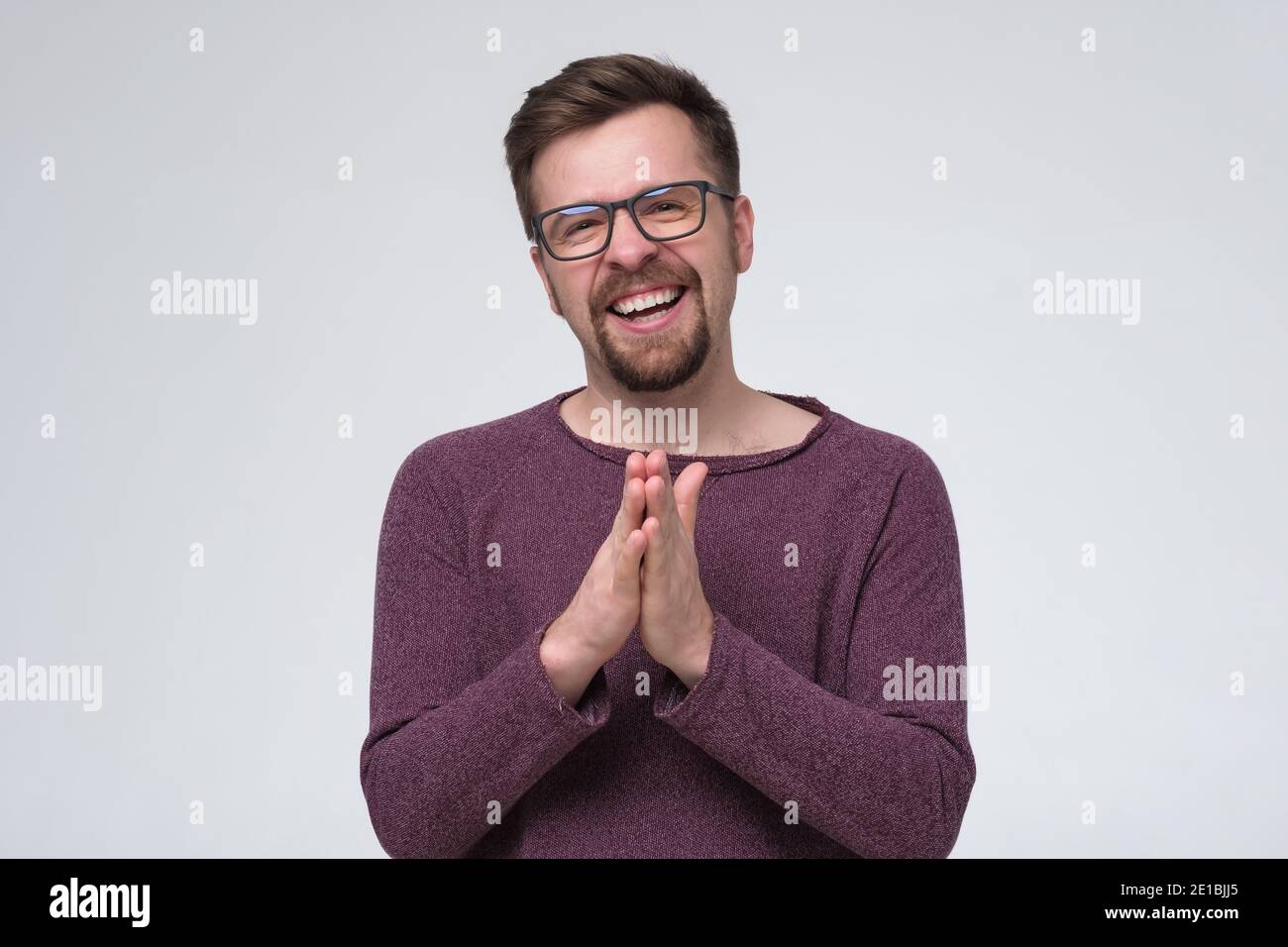 Smiling young man with beard and glasses looking at camera. Studio shot. Stock Photo
