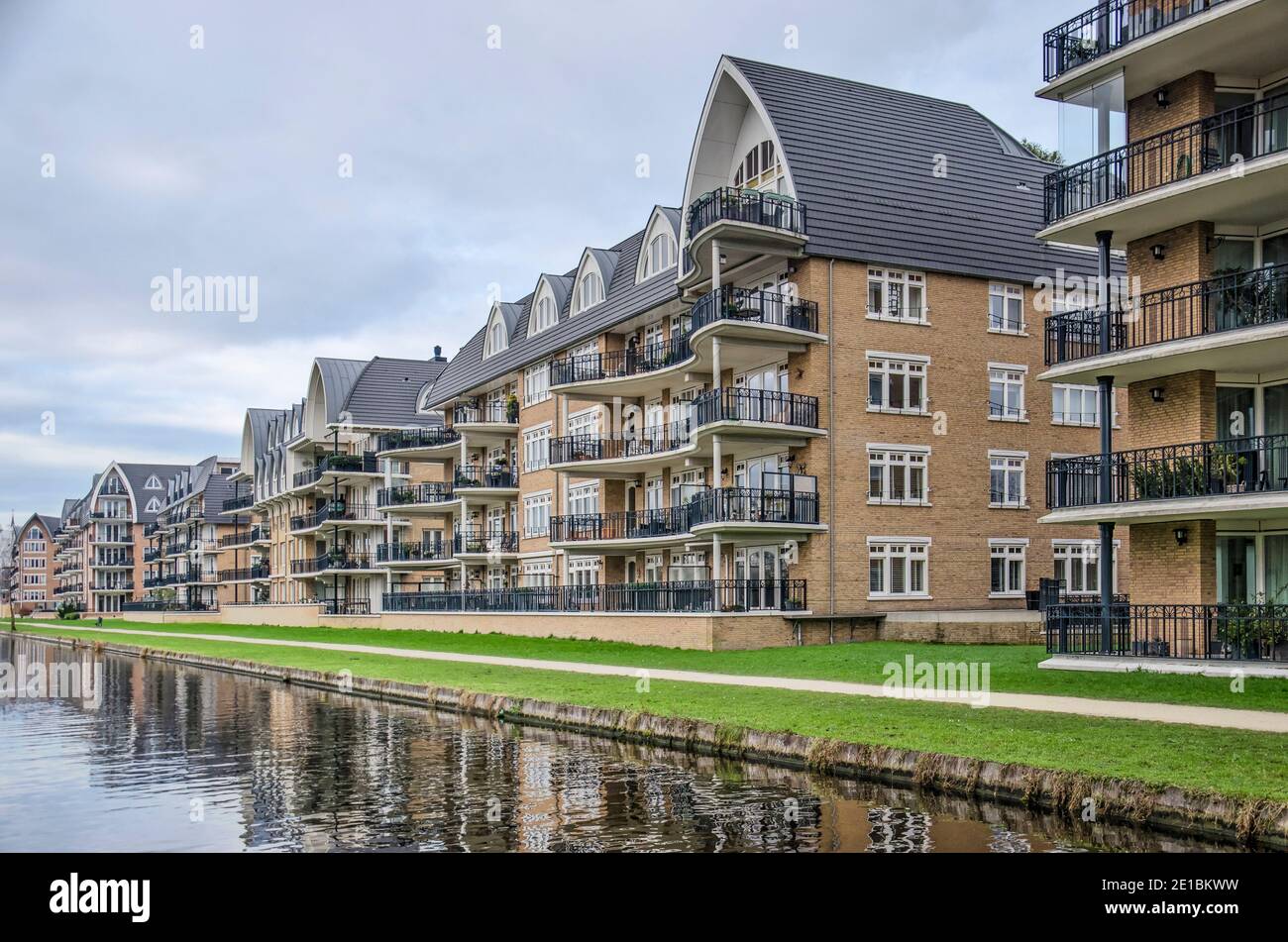 Voorschoten, The Netherlands, January 3, 2021: row of apartment blocks along a canal in Krimwijk neighbourhood with brick facades in post-modern eclec Stock Photo