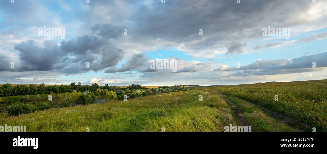 Summer panoramic landscape with rural road and dark rainy clouds over ...