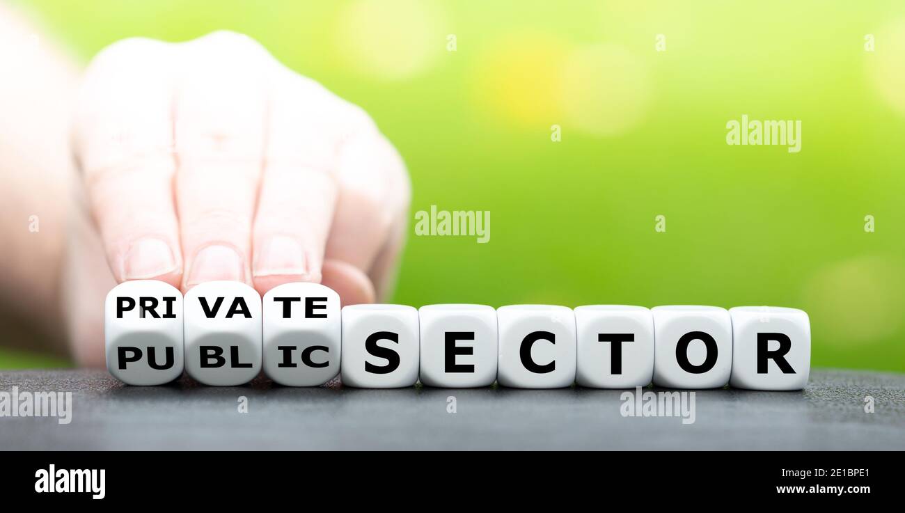 Hand turns dice and changes the expression 'public sector' to 'private sector'. Stock Photo