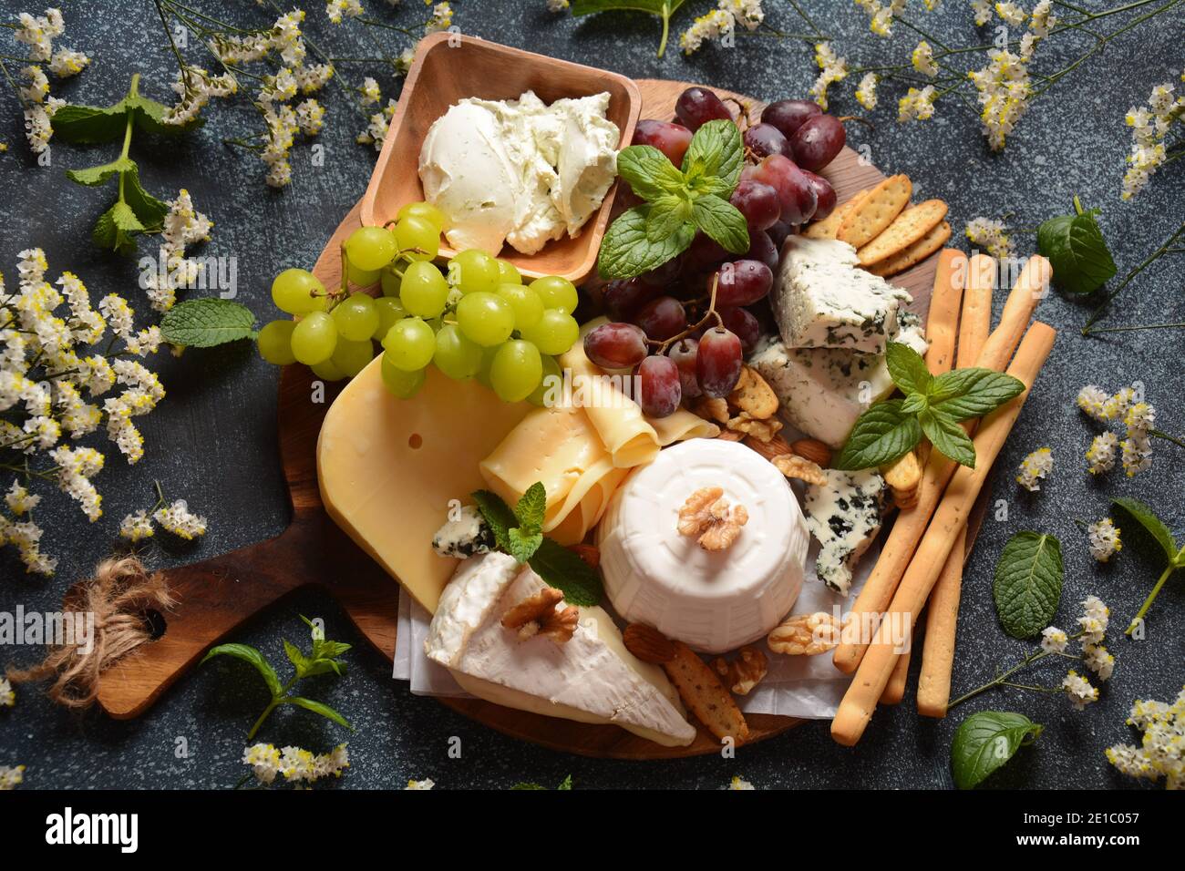 Cheese platter with assorted cheeses, grapes, nuts and snacks . Italian, French cheese starter. Traditional Shavuot Jewish Holiday food concept Stock Photo