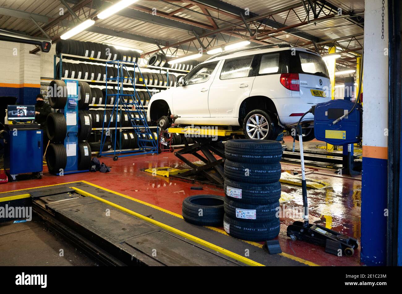 Kwik Fit motor vehicle tyre and exhaust repair and replacement facility white car with front wheel removed for puncture repair Stock Photo