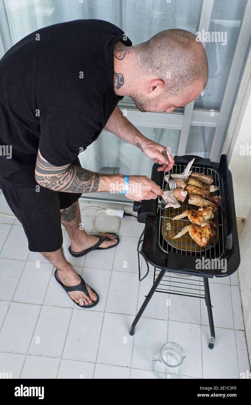 tattooed young man prepares and small very simple barbecue Stock Photo