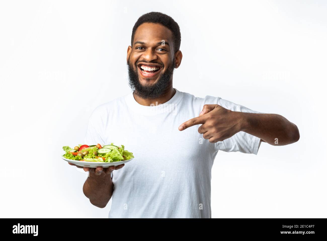 Cheerful Black Guy Pointing Finger At Salad Over White Background Stock Photo