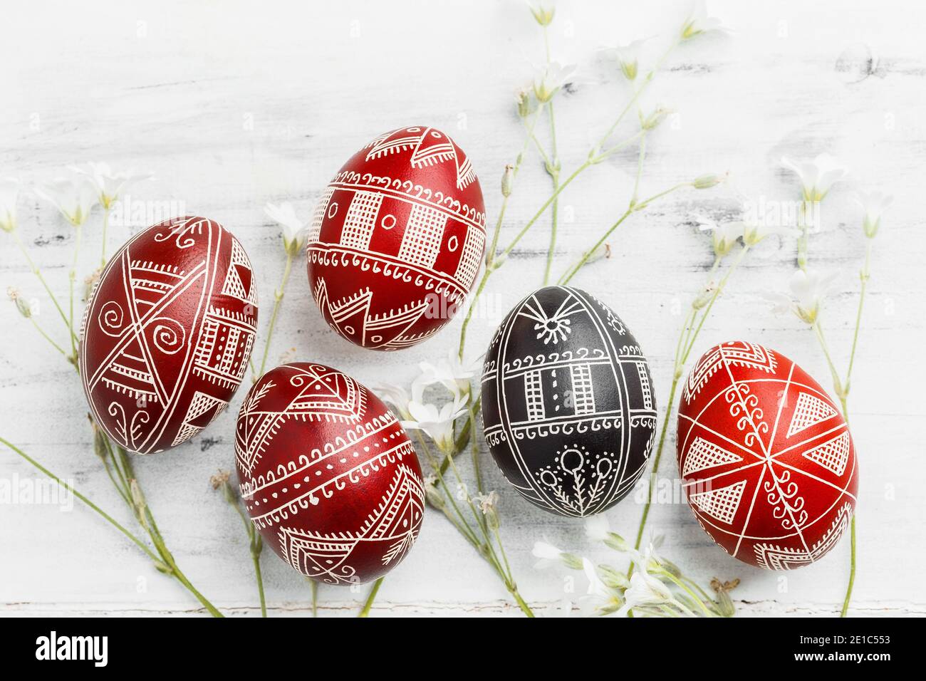 Red and black handmade Easter Pysanka eggs. Ukrainian pysanky decorated with wax-resist dyeing technique. White wooden background Stock Photo
