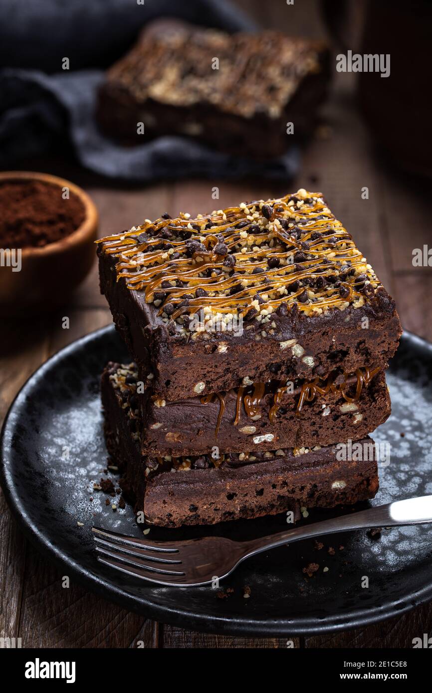 Dark chocolate fudge brownie with caramel and nut topping stacked on a