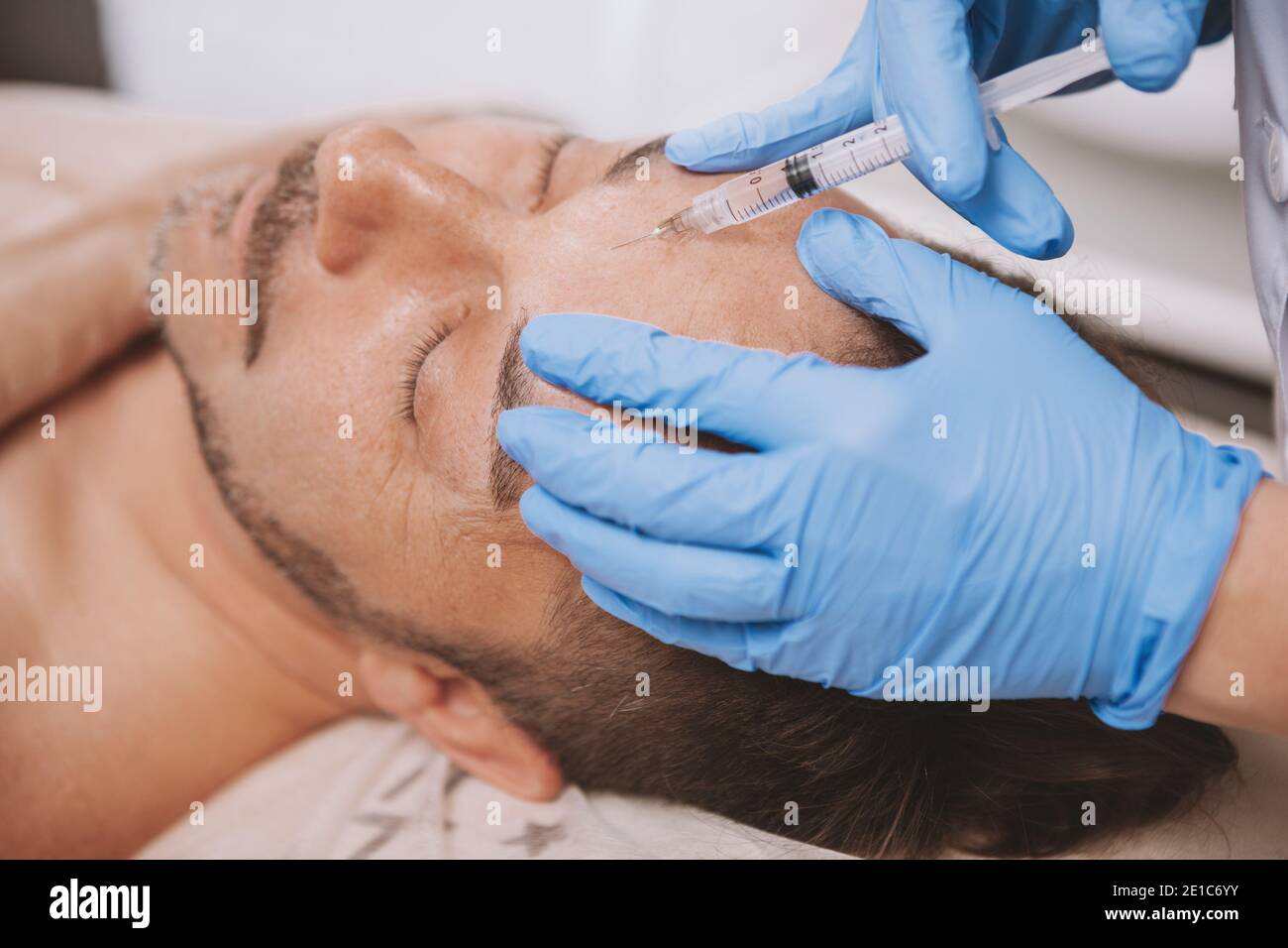 Mature man receiving facial filler injections by professional cosmetologist. Mid-aged man getting anti-wrinkle treatment at beauty salon. Botox, dispo Stock Photo