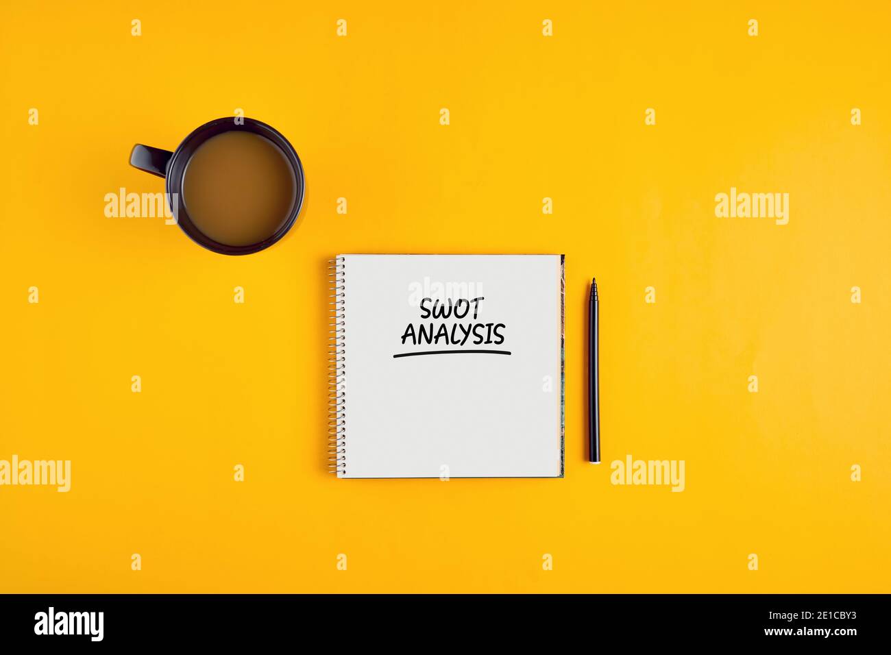 SWOT analysis written on notebook with pen and coffee mug on yellow background. Marketing strategy concept. Stock Photo