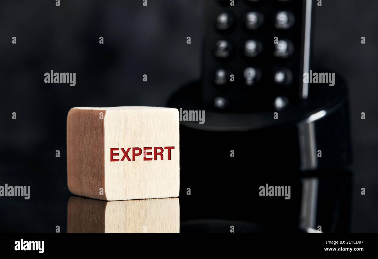 The word expert on wooden block with telephone background. Asking for expert advice concept. Stock Photo