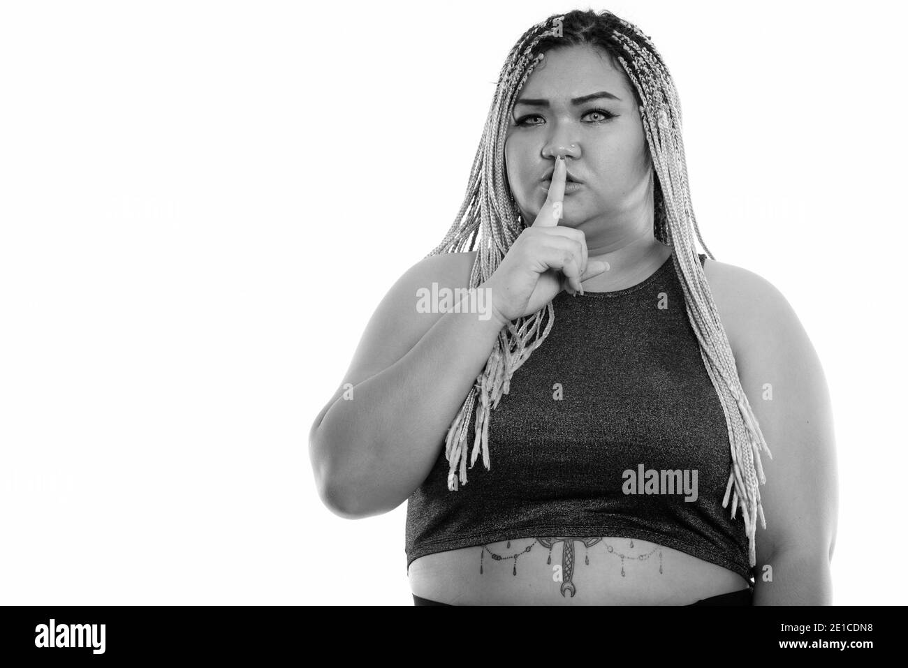 Studio shot of young fat Asian woman with finger on lips Stock Photo