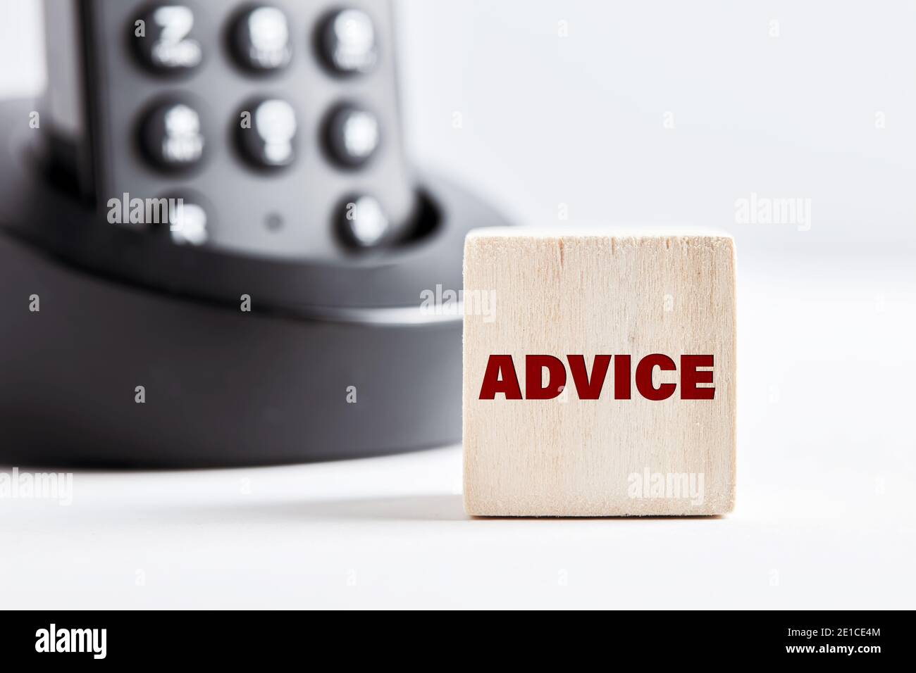 The word advice on wooden block with telephone background. Business concept for financial services, assistance, expertise or legal consultancy. Stock Photo