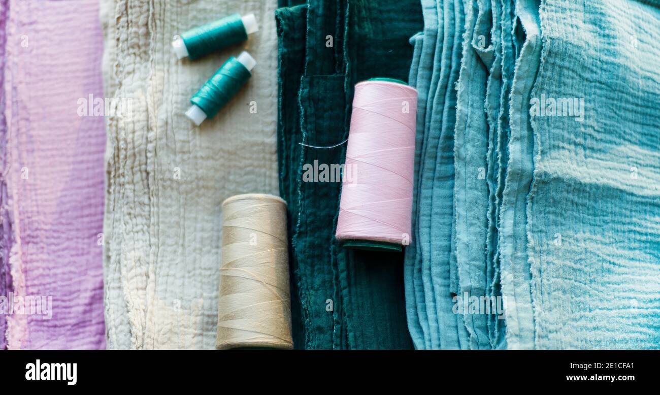 Four pieces of muslin and a thread of the same color. Backgrounds for seamstress needlework and garment textile production. Sewing and hobbies. Stock Photo