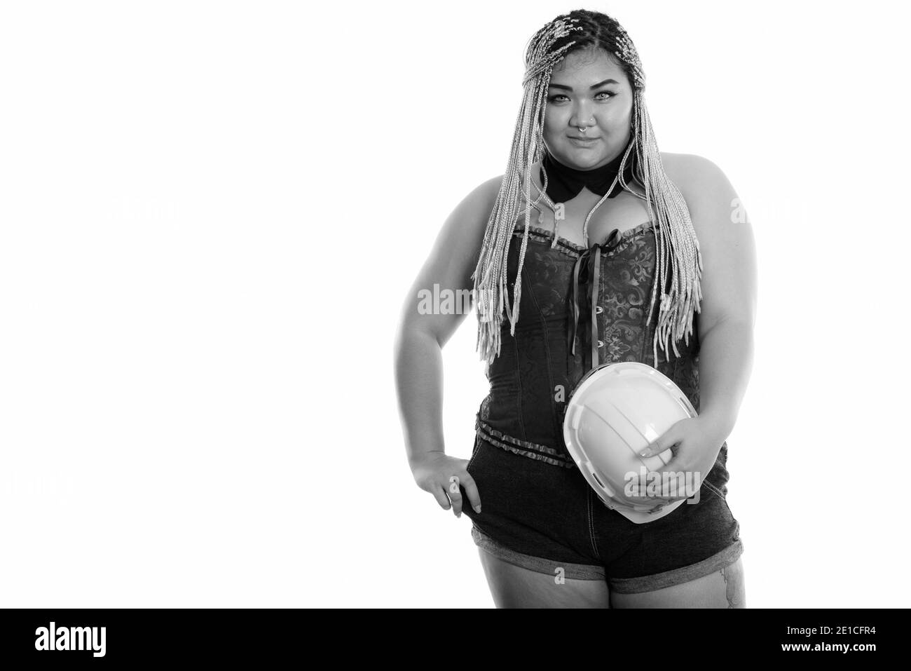Young fat Asian construction woman holding safety helmet while posing Stock Photo