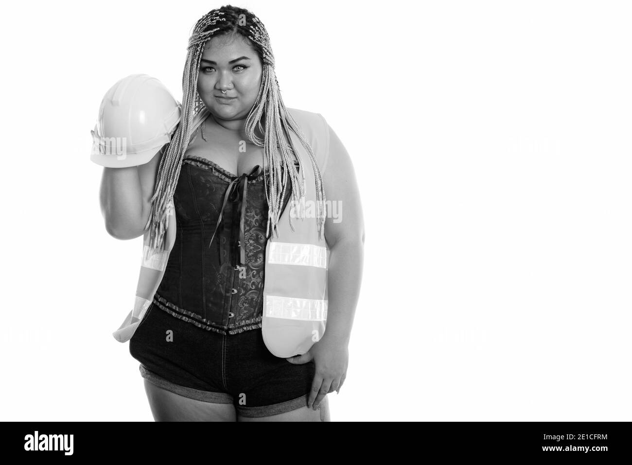 Young fat Asian construction woman holding and raising safety helmet Stock Photo