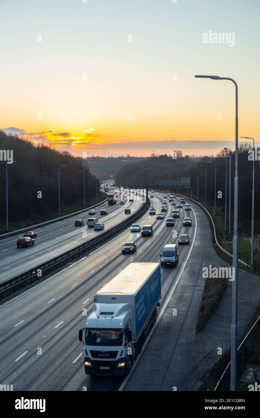 Manchester, England, UK. 6th Jan 2021. The sun sets after a clear, cold day over a winding section of the M60 Manchester Outer Ring Road motorway on the first day of national lockdown in England. Despite lockdown, significant levels of traffic populated all four lanes of the motorway in the Whitefield/Prestwich area as pictured. Credit: Callum Fraser/Alamy Live News Stock Photo