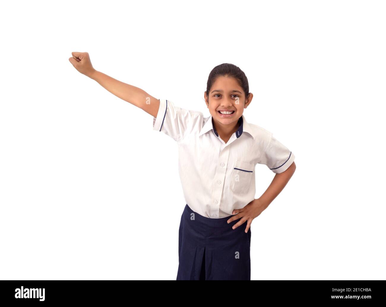 Portrait of a excited, confident and smiling Indian school girl in uniform  with right arm outstretched depicting achievement and victory Stock Photo