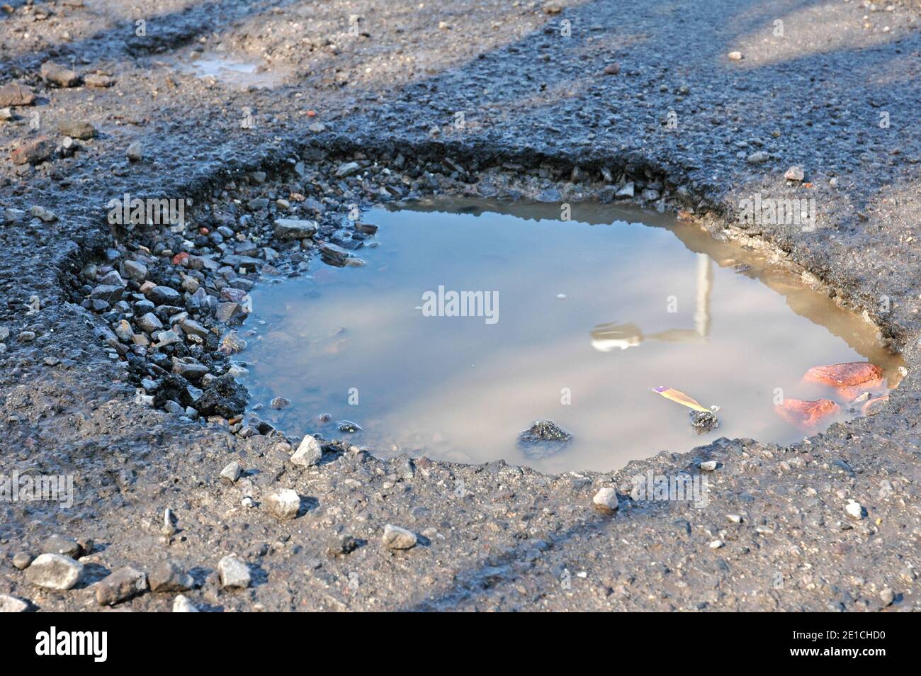 Water damage to tarmac in lane.  West Sussex Coastal Plain, Chichester Plain, England, UK.  March. Stock Photo
