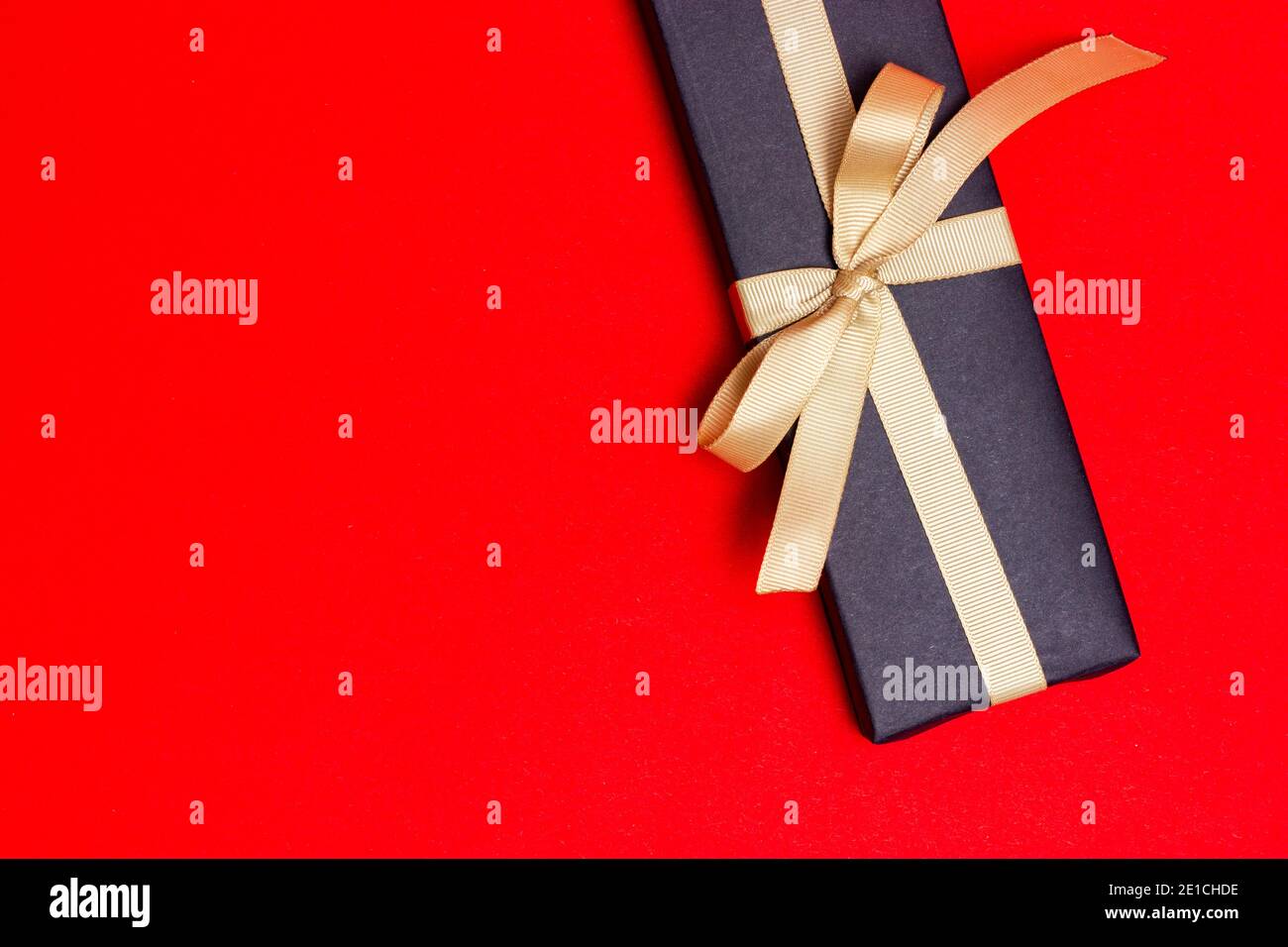 Gift with a white paper note wrapped in black paper on a red background ...