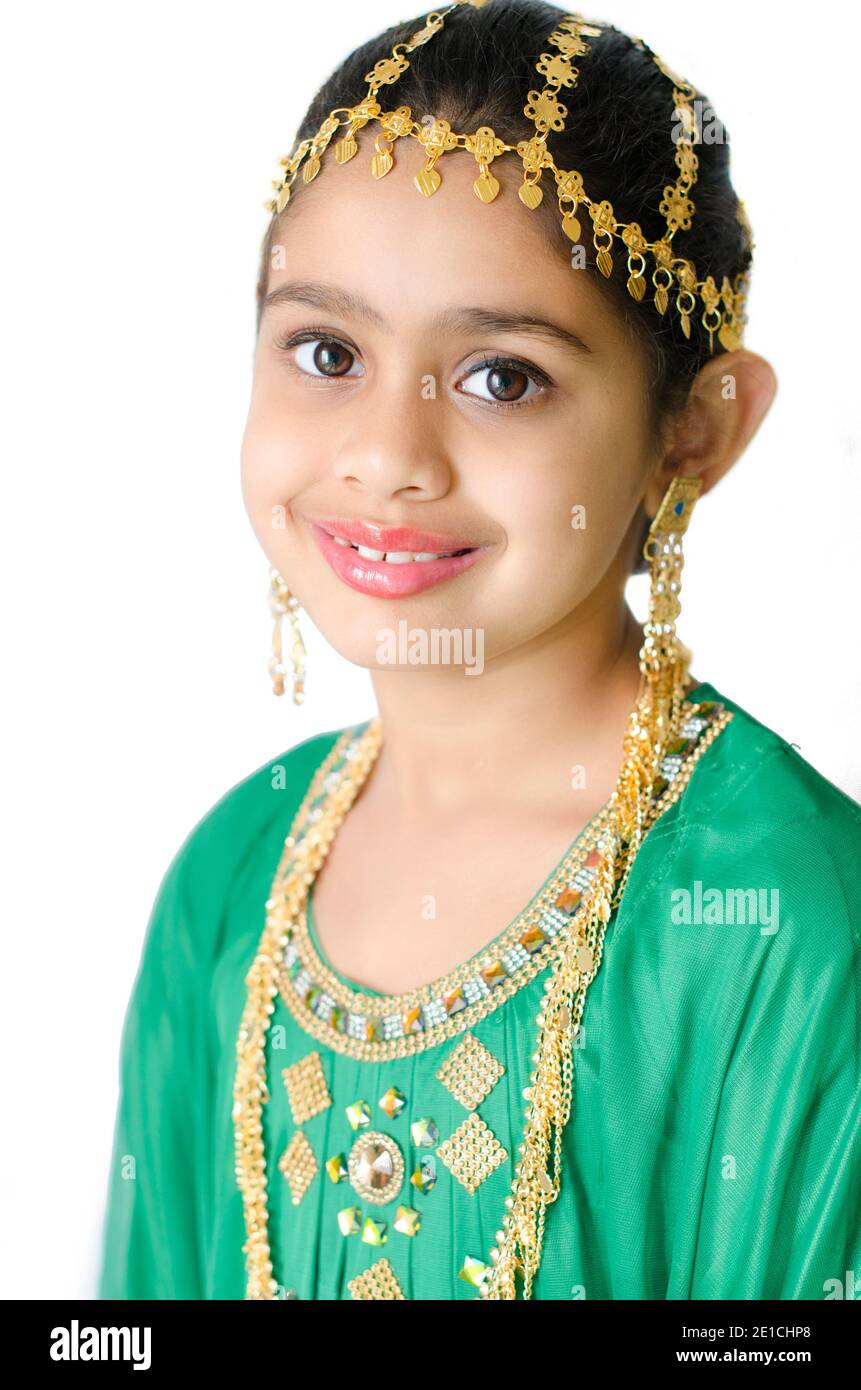 PORTRAIT OF A GIRL WEARING A TRADITIONAL ARABIC GREEN DRESS WITH GOLD EAR RING, HEAD AND NECK JEWELLERY. Stock Photo