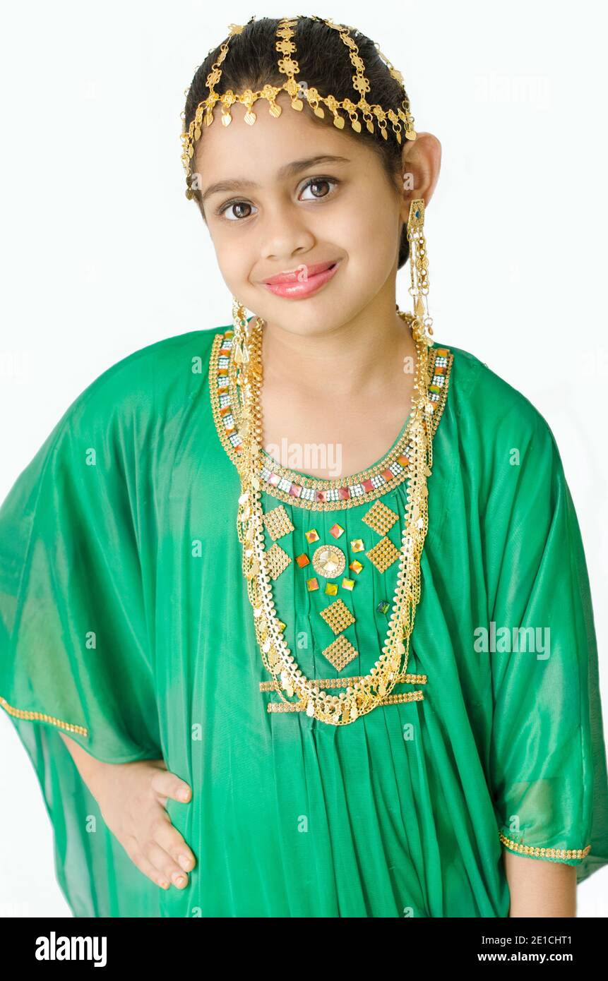 PORTRAIT OF A GIRL WEARING A TRADITIONAL ARABIC GREEN DRESS WITH GOLD EAR RING, HEAD AND NECK JEWELLERY. Stock Photo
