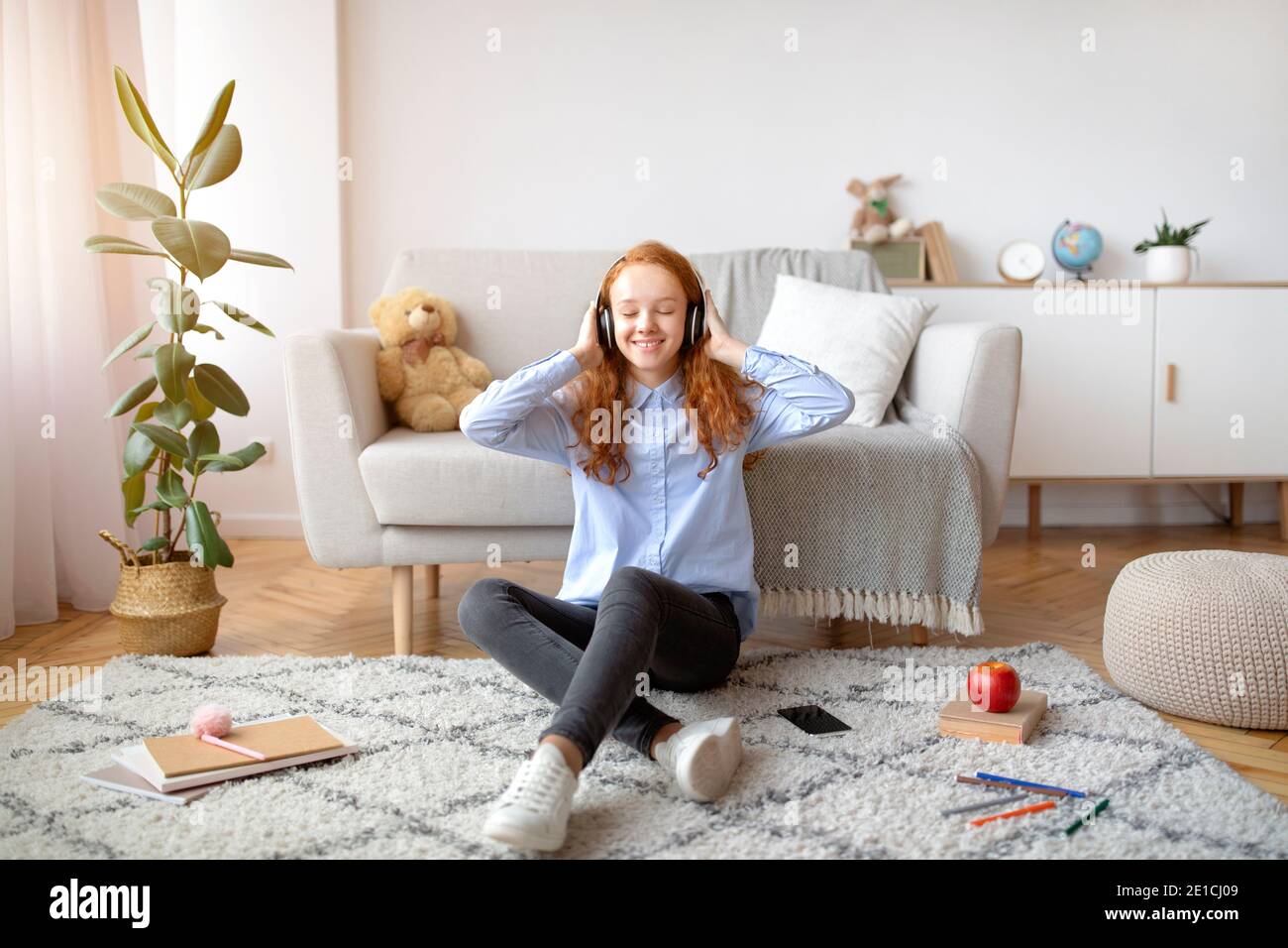 Teenage girl sitting on floor carpet, listening to music Stock Photo ...