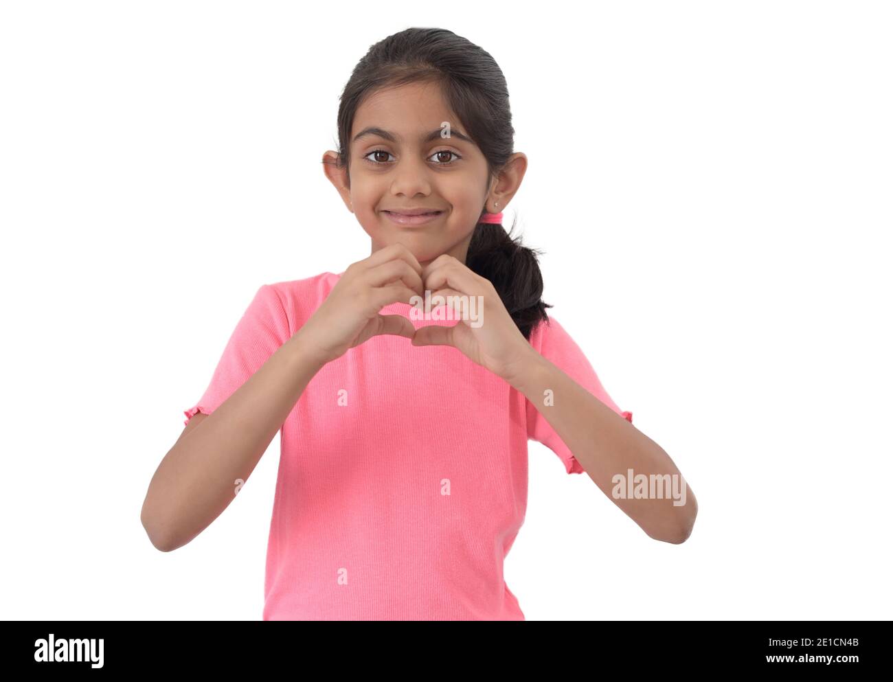 Portrait of a cute little indian girl showing heart shape sign with hands and expressing love. Stock Photo