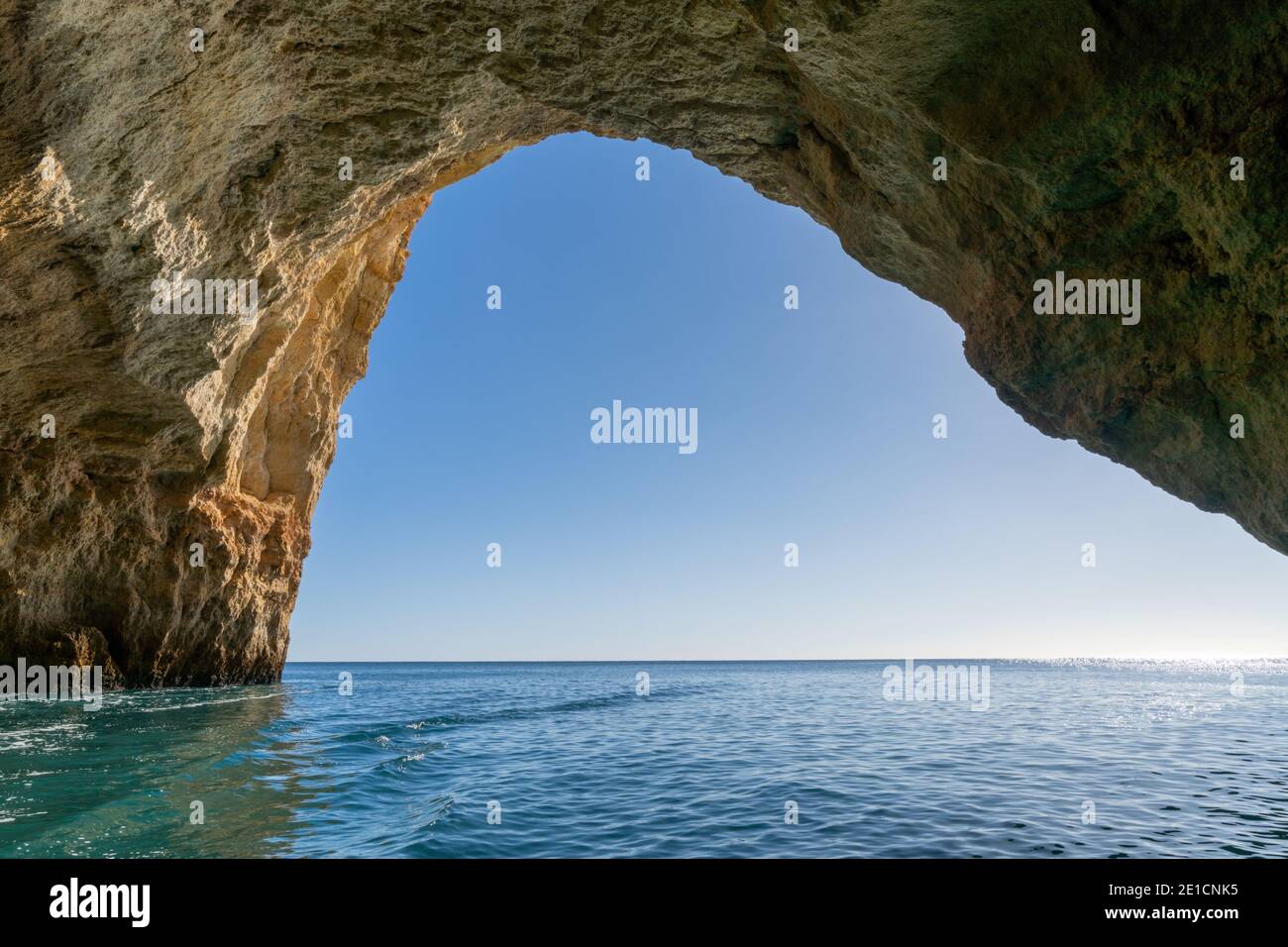A view from inside a cave on the ocean coast with turquoise water and sunny blue sky outside Stock Photo