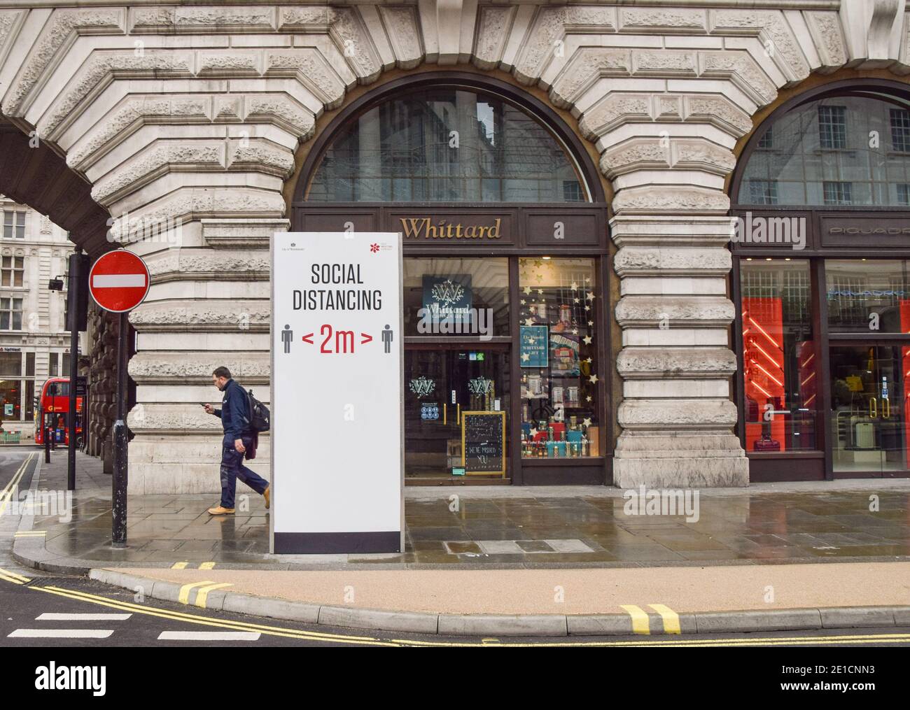 A man walks past a social distancing sign on an empty Regent Street in London, during the third national coronavirus lockdown in England. Stock Photo