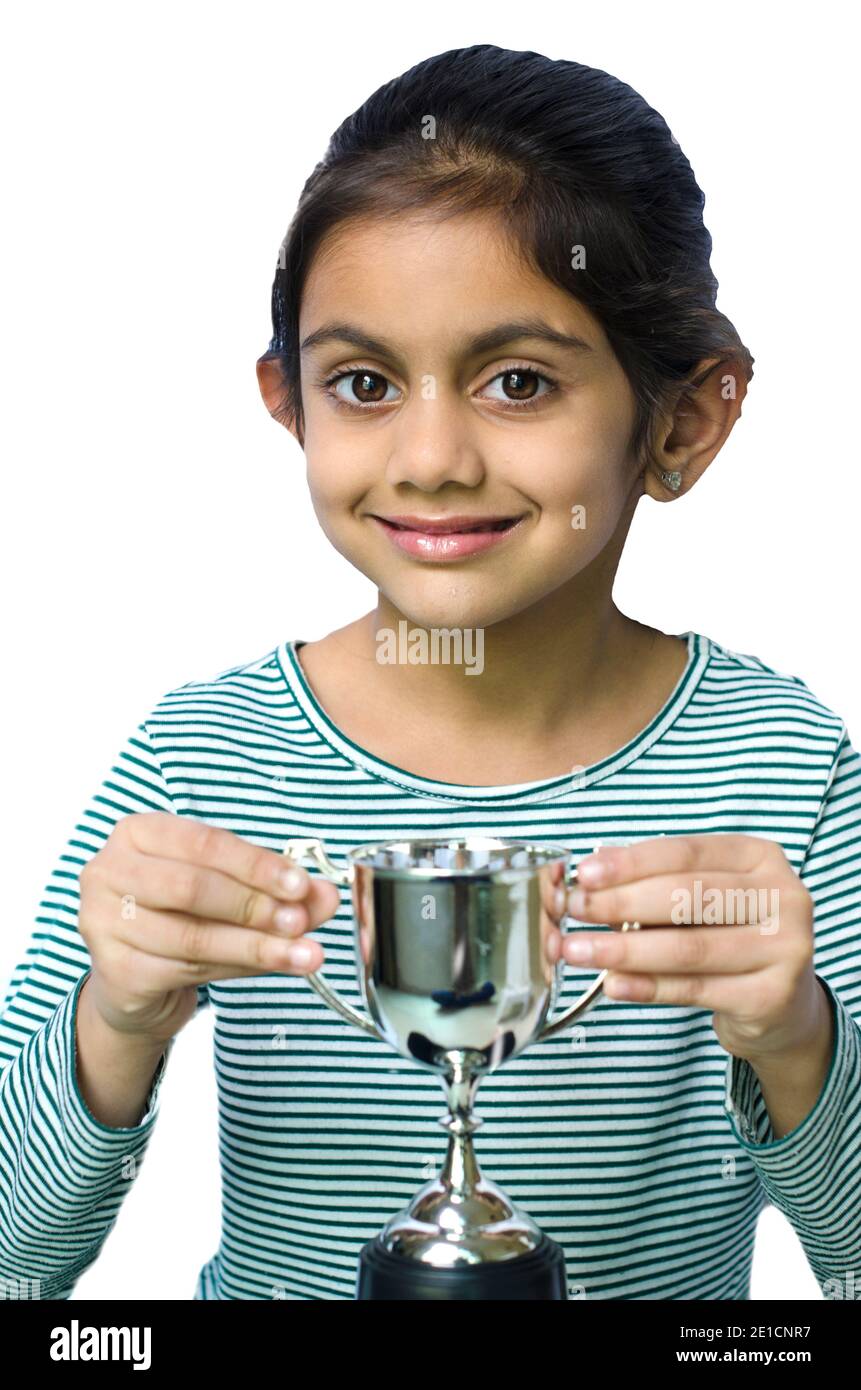 A beautiful and smiling indian girl holding a silver trophy and depicting victory. Stock Photo