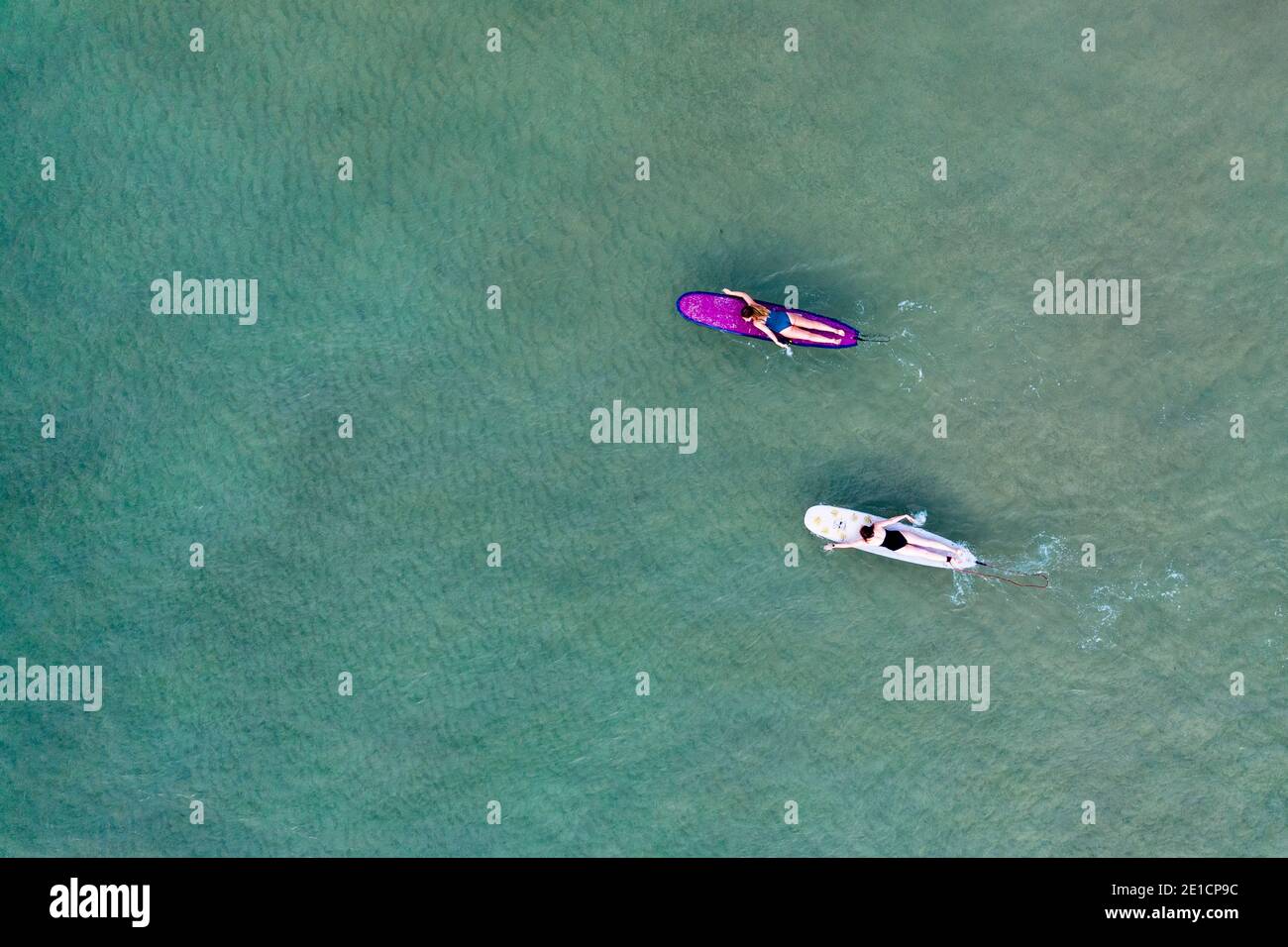 Two women are paddling their surfboards seen from above at Little Cove, Noosa Heads, Queensland, Australia Stock Photo