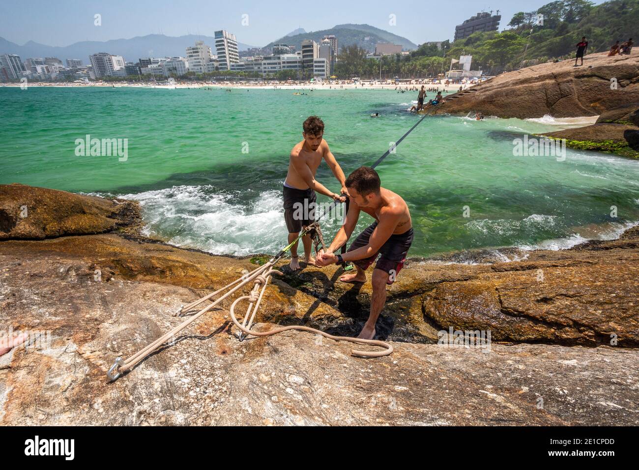 Friends setting up waterline in Arpoador Rock, Ipanema Beach, Rio de Janeiro, Brazil Stock Photo