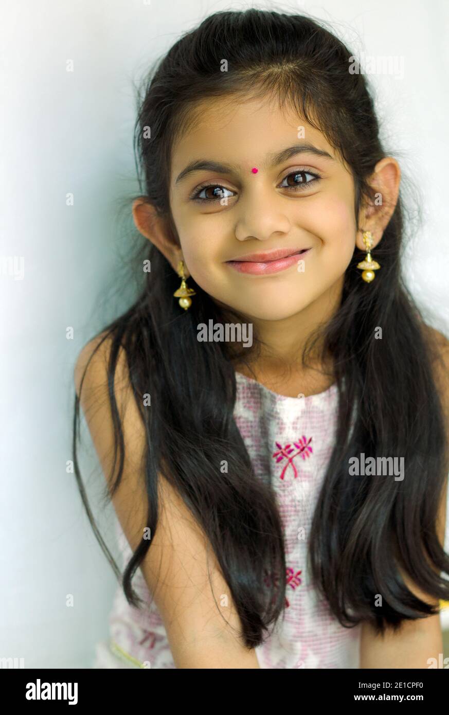 Portrait of a beautiful smiling Indian cute girl   Dressed in traditional Indian costume with brown eyes and long hair. Stock Photo