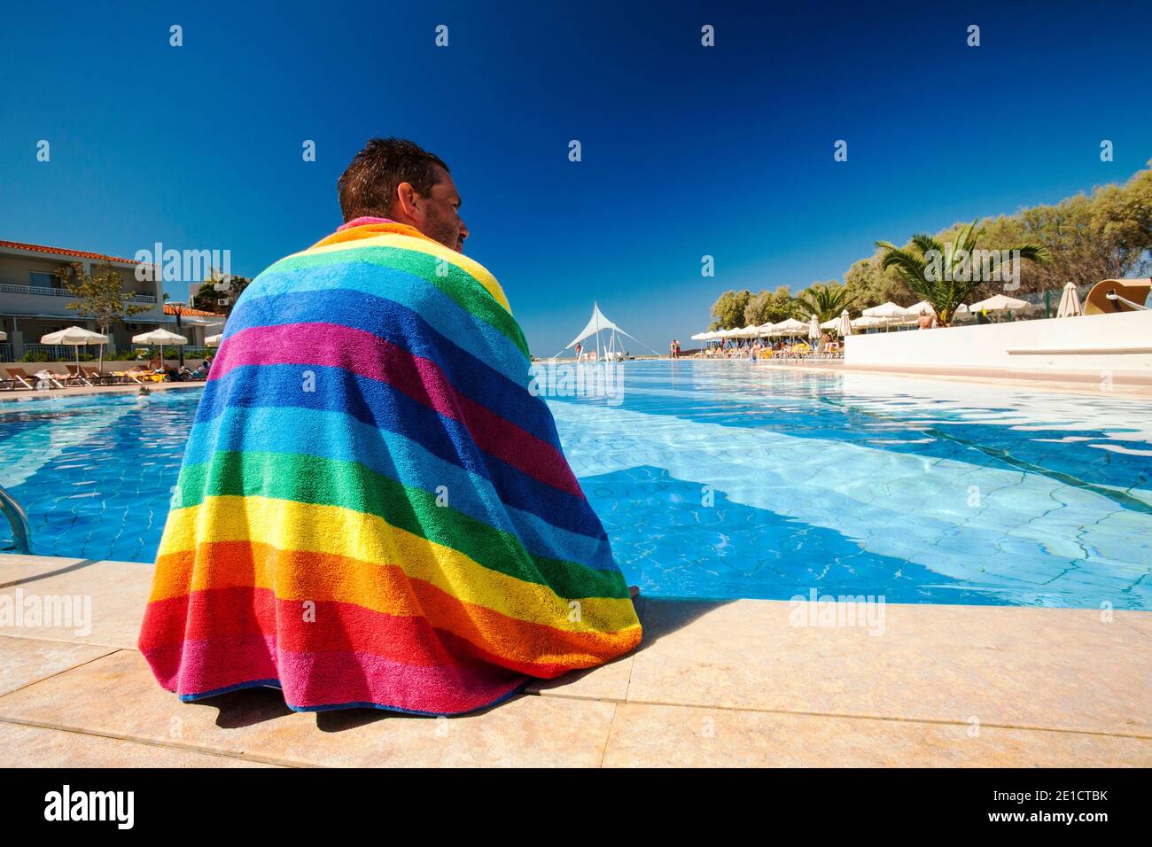 A man sat around a swimming pool at a holiday complex in Myrina on Lemnos, Greece. Stock Photo